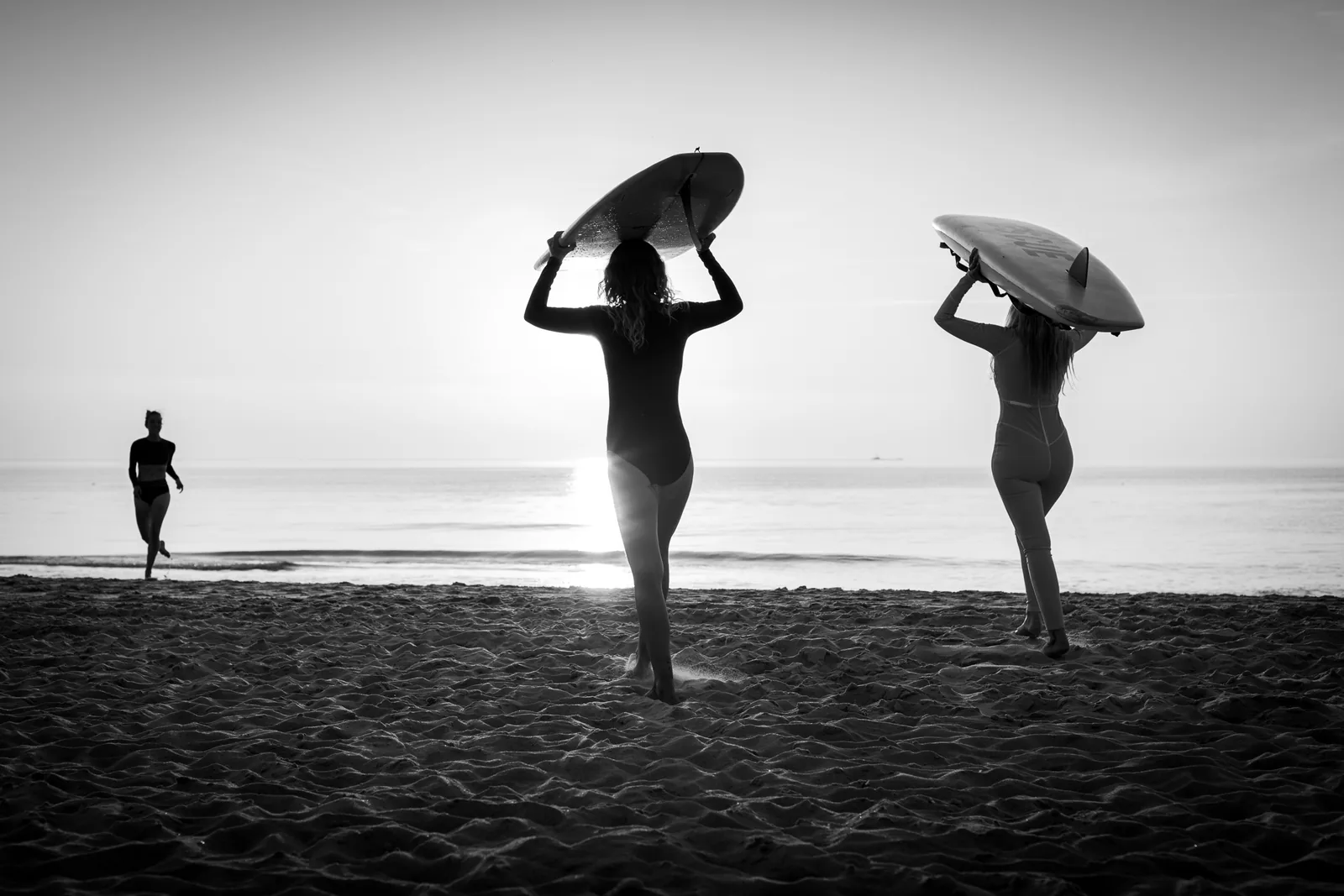 Fine-Art-Print Sylt — Surferinnen mit Boards im Gegenlicht am Strand, Schwarz-Weiß