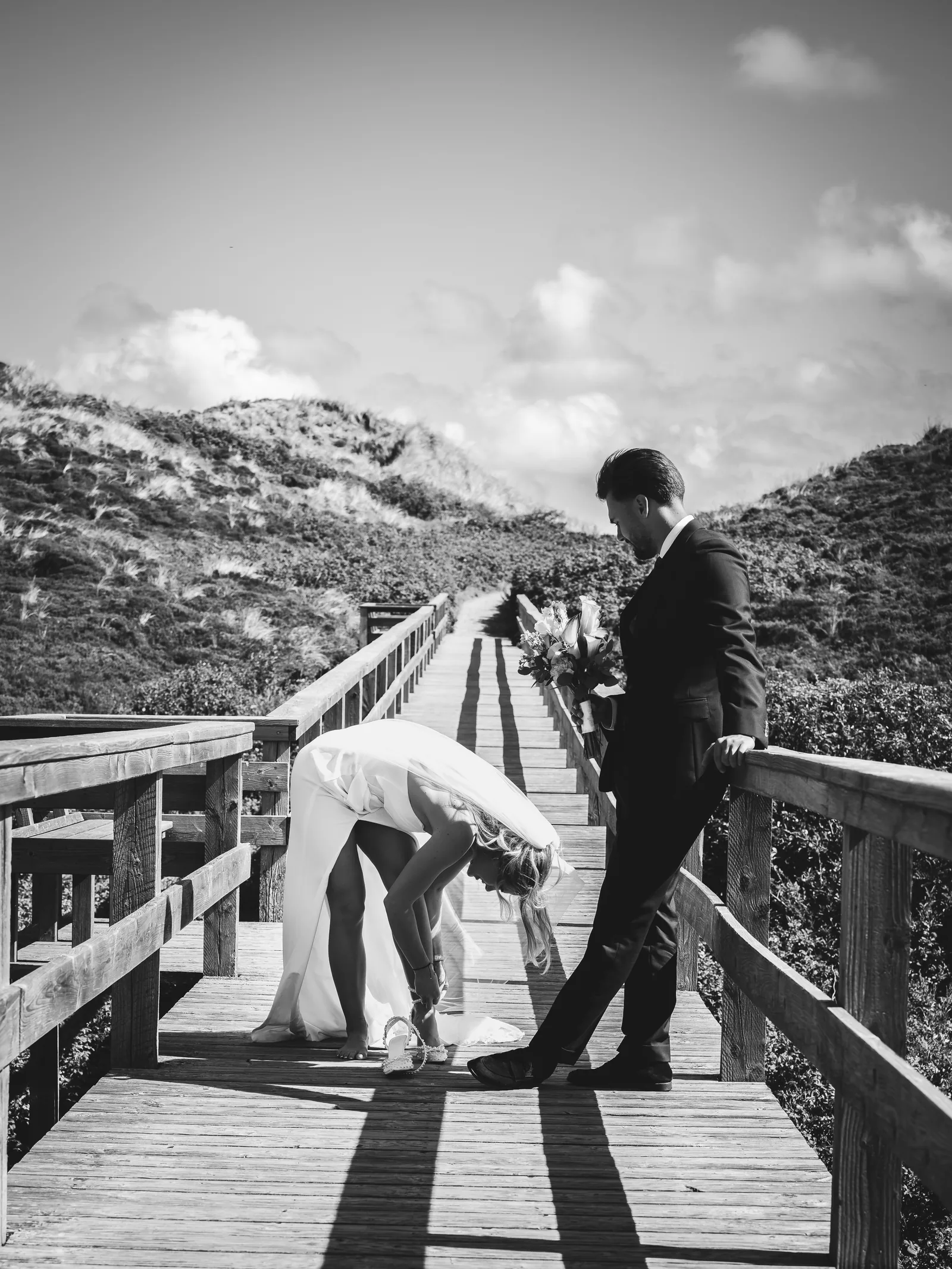 Hochzeitsfotografie Sylt — Brautpaar auf dem Bohlenweg durch die Dünen